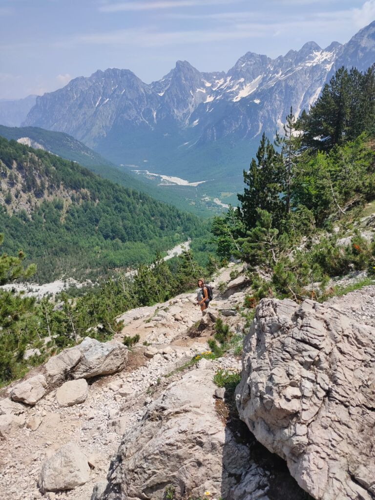 Snow caped mountains and green hills on the trail down in the hike from Theth to Valbona with a baby