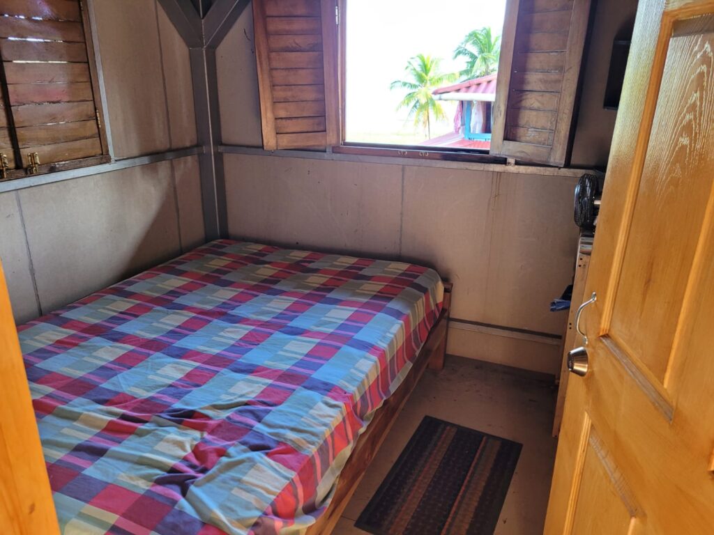 One double bed in a small room with a window facing the sea 