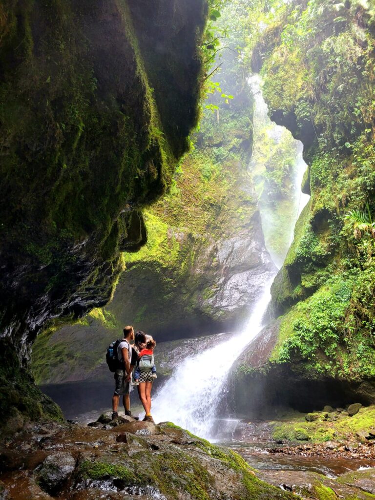 Three people looking at a waterfall with rock formations around 